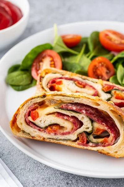 Italian food Pizza roll stromboli with cheese, salami, spinach and red pepper a light background. — Stock Photo, Image