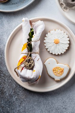 Paskalya tatili için masa ayarı. Fotoğraf beyaz yemekler gösterir, bir peçete içinde mat, Paskalya yumurtası hizmet. Peçete tavşan kulakları altında dökümlü.