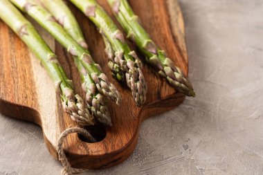 Kırsal ahşap bir masada taze yeşil kuşkonmaz mızrakları.