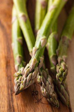 Kırsal ahşap bir masada taze yeşil kuşkonmaz mızrakları.