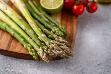 Tasty fresh vegetables for dinner or lunch ready to be cooked with ripe cherry tomatoes, lime, asparagus, eggs and olive oil.