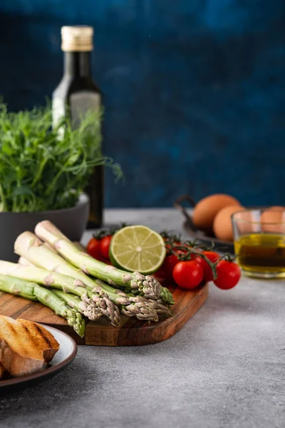 Tasty fresh vegetables for dinner or lunch ready to be cooked with ripe cherry tomatoes, lime, asparagus, eggs and olive oil. — Stok fotoğraf