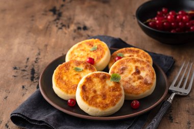 Cottage cheese pancakes Russian syrniki with red currant and yogurt, selective focus.