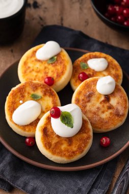 Cottage cheese pancakes Russian syrniki with red currant and yogurt, selective focus.