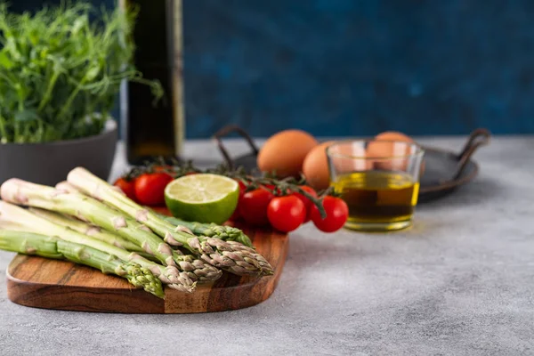 Tasty fresh vegetables for dinner or lunch ready to be cooked with ripe cherry tomatoes, lime, asparagus, eggs and olive oil. — Stok fotoğraf