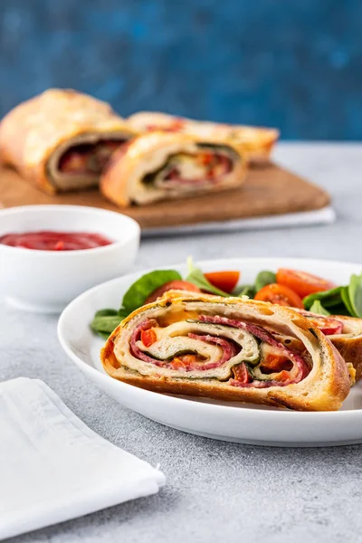 Italian food Pizza roll stromboli with cheese, salami, spinach and red pepper a light background. — Stock Photo, Image