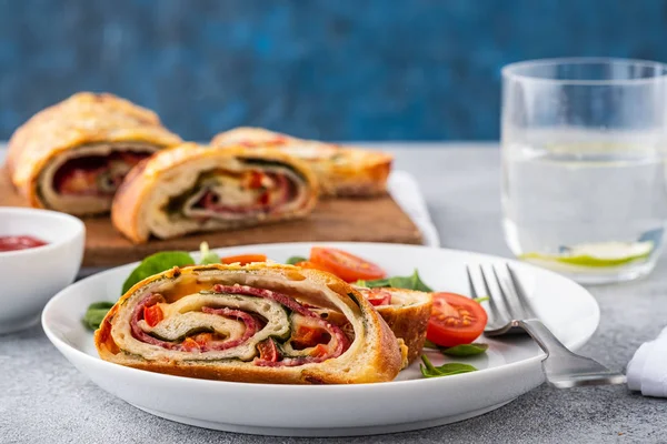 Italian food Pizza roll stromboli with cheese, salami, spinach and red pepper a light background. — Stock Photo, Image