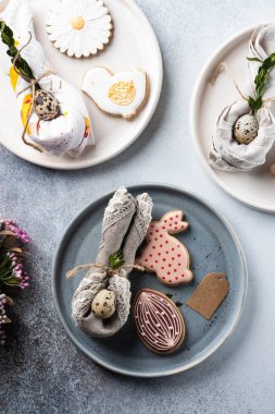 Paskalya tatili için masa ayarı. Fotoğraf beyaz yemekler gösterir, bir peçete içinde mat, Paskalya yumurtası hizmet. Peçete tavşan kulakları altında dökümlü.