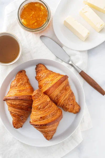 Frühstück mit Croissants, Tee und Orangenmarmelade. — Stockfoto