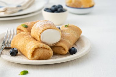 Crepes, thin pancakes with cream cheese and fresh blueberries.