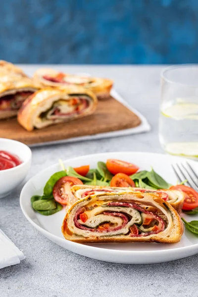 Italiensk mat Pizzarulle stromboli med ost, salami, spenat och röd paprika en lätt bakgrund. — Stockfoto