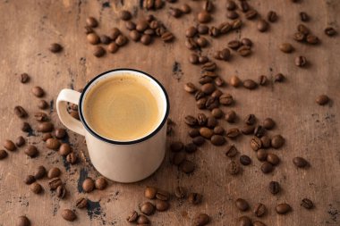 Beyaz kahve fincanı ve eski ahşap zemin üzerinde kahve çekirdekleri.