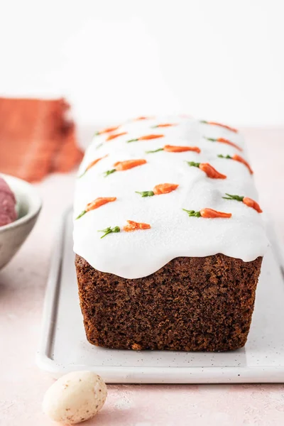 Sabroso pastel de esponja de zanahoria de Pascua con crema y pequeñas zanahorias sobre fondo rosa . — Foto de Stock