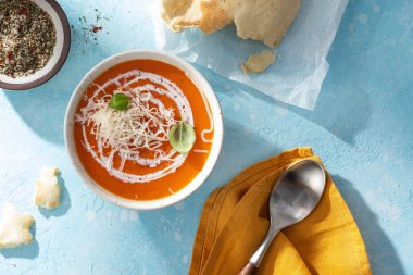 Balkabağı ve havuç çorbası kremalı ve bazilikli mavi taş arka plan manzaralı.