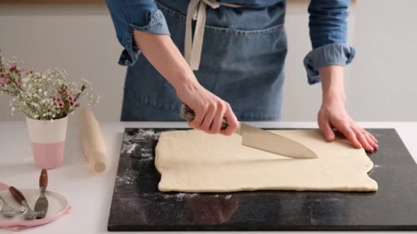 Kobiece ręce piekarza pokroiły ciasto cienkim nożem w domowej kuchni. Domowej roboty świeże pyszne bułki ciasta i rogaliki. Jedzenie wolno poruszające się. — Wideo stockowe