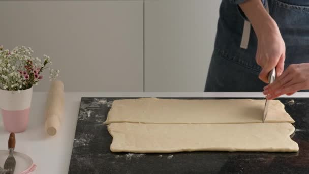 Vrouwelijke handen van een bakker snijden het deeg met een dun mes in de huiskeuken. Zelfgemaakte verse heerlijke gebakjes broodjes en croissants. — Stockvideo