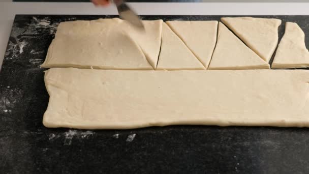 Vrouwelijke handen van een bakker snijden het deeg met een dun mes in de huiskeuken. Zelfgemaakte verse heerlijke gebakjes broodjes en croissants. — Stockvideo