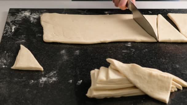 Kvinnliga händer på en bagare skär degen med en tunn kniv i hemköket. Hemlagade färska läckra bakverk bullar och croissanter. — Stockvideo