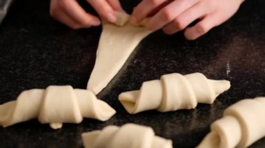 Dişi bir fırıncı pişirmeden önce güzel bir kruvasana dönüşür. Ev yapımı lezzetli hamur işleri çörekler ve kruvasanlar. Geleneksel İtalyan aile pastanesi. Kruvasan ve salyangoz. Yavaş yemek..