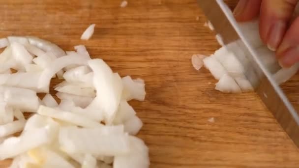 Frauenhände schneiden eine Zwiebel auf einem Schneidebrett aus nächster Nähe in Stücke. Suppe kochen. — Stockvideo