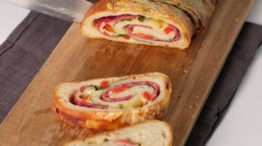 Kadın elleri İtalyan yemeklerini kesiyor peynirli pizza rulo stromboli, mozzarella, salam, domates, ıspanak ve kırmızı biber.