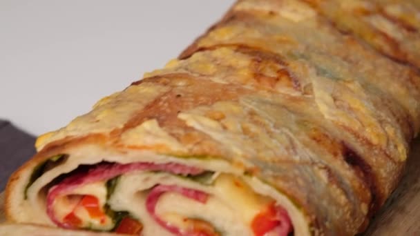 Italian food Pizza roll stromboli with cheese, mozzarella, salami, tomatoes, spinach and red pepper a light background. — Stock Video