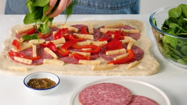 Female hands making italian food. Pizza roll. Stromboli with cheese, mozzarella, salami, tomatoes, spinach and red pepper on a light table. — Stock Video