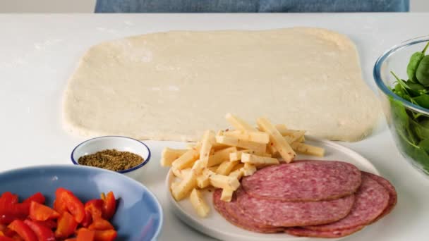 Female hands making italian food. Pizza roll. Stromboli with cheese, mozzarella, salami, tomatoes, spinach and red pepper on a light table. — Stock Video