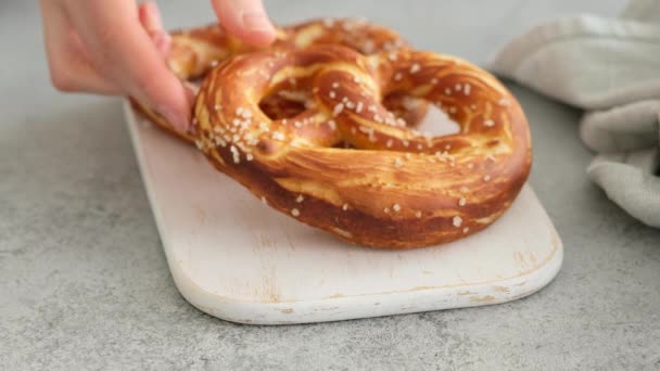 Oktoberfest menu de comida, pretzels macios e cerveja em uma tábua de madeira e fundo branco. A cerveja é derramada. Copo misturado com cerveja. Mãos femininas tomar britzel . — Vídeo de Stock