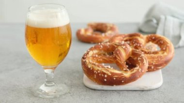 Oktoberfest yemek menüsü, yumuşak krakerler ve tahta tahtada bira ve beyaz arka plan. Bira döküldü. Birayla karıştırılmış cam. Kadın elleri Britzel 'i alır.