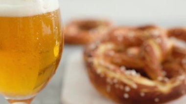 Oktoberfest yemek menüsü, yumuşak krakerler ve tahta tahtada bira ve beyaz arka plan. Bira döküldü. Birayla karıştırılmış cam..