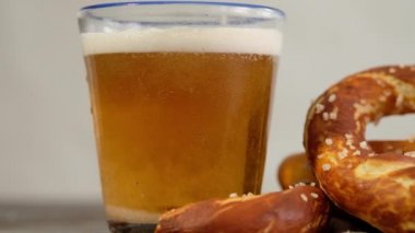 Oktoberfest yemek menüsü, yumuşak krakerler ve tahta arka planda bira. Bira dolduruluyor. Birayla karıştırılmış cam. Yavaş çekim.