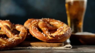 Oktoberfest yemek menüsü, yumuşak krakerler ve tahta arka planda bira. Bira dolduruluyor. Birayla karıştırılmış cam. Yavaş çekim.