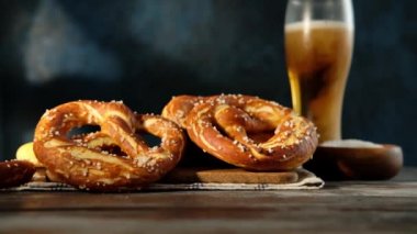 Oktoberfest yemek menüsü, yumuşak krakerler ve tahta arka planda bira. Bira dolduruluyor. Birayla karıştırılmış cam. Yavaş çekim.