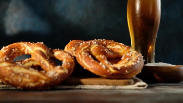 Oktoberfest yemek menüsü, yumuşak krakerler ve tahta arka planda bira. Bira dolduruluyor. Birayla karıştırılmış cam. Yavaş çekim. — Stok video
