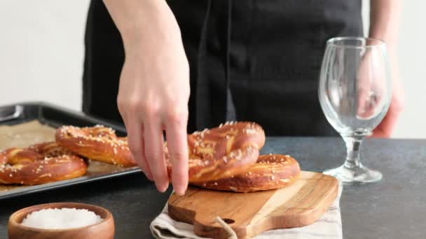 Oktoberfest food menu, soft pretzels and beer on a wooden board and dark background. Beer is poured. Misted glass with beer. Female hands take britzel. — Stock Video