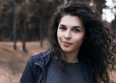 Güzel esmer genç kadın parkta kamera bakıyor. Açık.