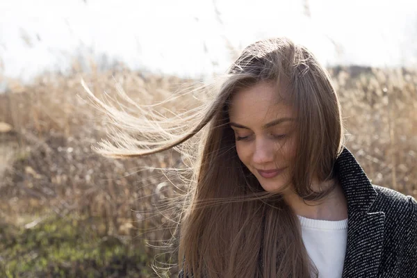 Yünlü bir ceket giymiş güzel genç kadın yan lara bakıyor ve gülümsüyor. Sonbahar. Açık. Headshot.