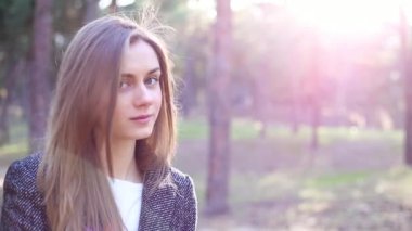 Kız parkta duruyor, kameraya bakmak için döner