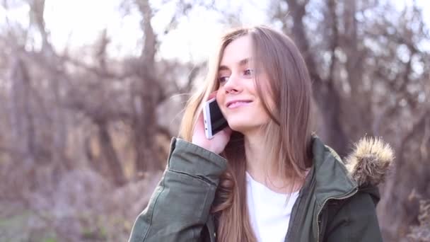 Young beautiful woman with blond hair is talking on the phone in park — Stock Video