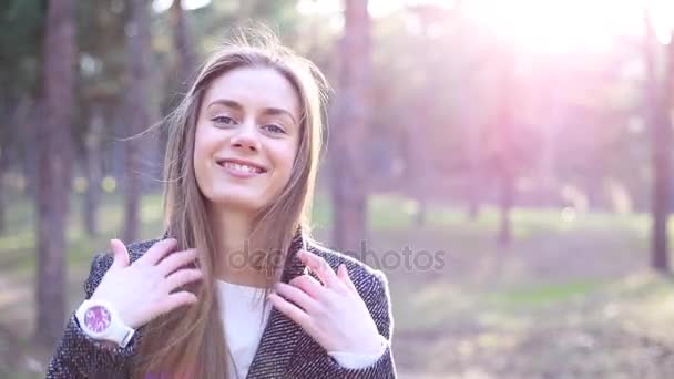 Flickan kör händerna genom håret ser på kameran och leende — Stockvideo