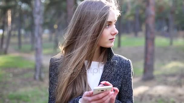 A menina pensou em algo e depois continuou a surfar algo no telefone — Vídeo de Stock