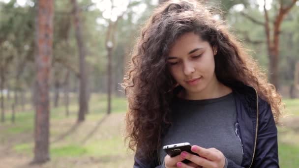 Женщина использует мобильный телефон в парке — стоковое видео