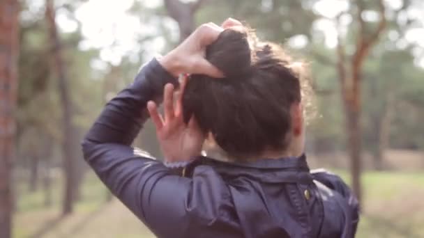 Girl braids her hair in a bun. From the back. — Stock Video