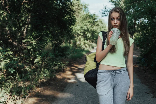 Spor genç kadın parklar yolda yürüyüş ve taze coctail içmek