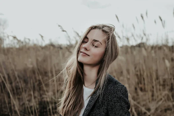 Muchacha muy hermosa y de moda con los ojos cerrados de pie sobre el fondo de la fiebre . — Foto de Stock