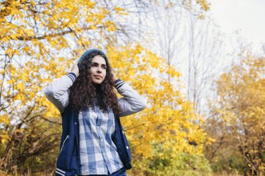 Kız sonbahar ormanda ayakta ve şapka düzeltiyor