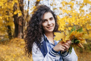 Yaprakları el avuç içinde tutan güzel kız