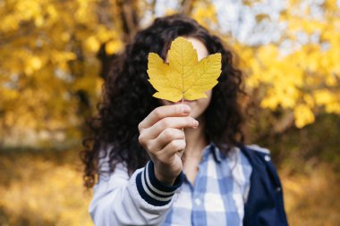 akçaağaç yaprağı tutan kıvırcık kadın