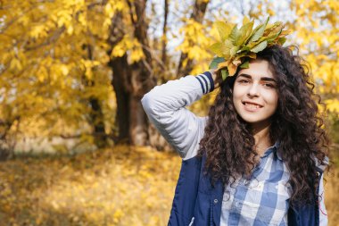 Çok güzel bir kadın kıvırcık saçlı grup yaprakları ile sonbahar park kamerada poz